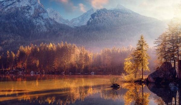 Fototapeta Awesome Nature Scenery. Beautiful Landscape With High Mountains With Illuminated Peaks, Stones In Mountain Lake, Reflection, Blue Sky And Yellow Sunlight In Sunrise. Amazing Nature Background.
