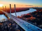 Fototapeta Beautiful Panoramic Aerial Drone View To Cable-Stayed Siekierkowski Bridge Over The Vistula River And Warsaw City Skyscrapers, Poland In Gold Red Autumn Colors In November Evening At Sunset